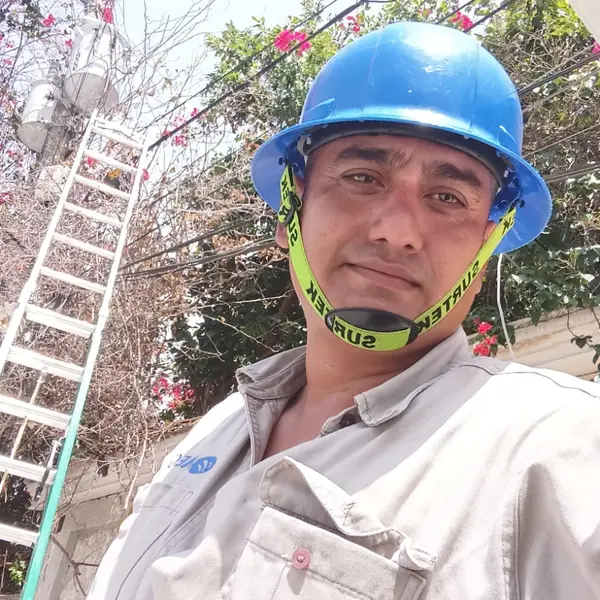 Jorge in hard hat next to his extension ladder