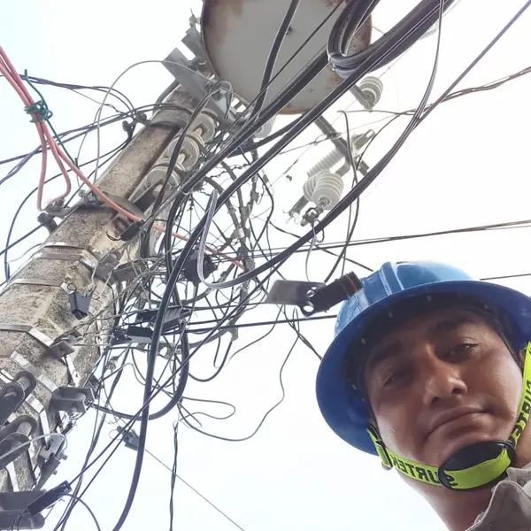 Jorge in hard hat beneath a utility pole